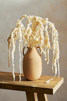 a vase filled with white flowers sitting on top of a wooden table