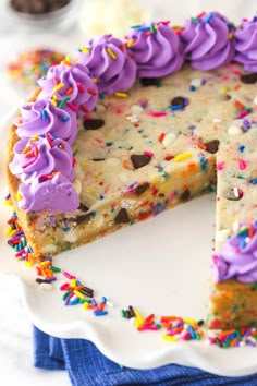 a white cake with purple frosting and sprinkles on the top slice