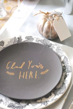 a plate with gold writing on it sitting on top of a white and black table cloth