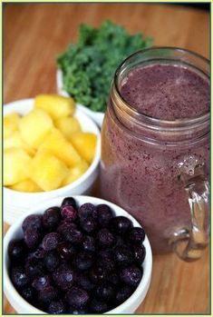 two bowls filled with blueberries and pineapple next to a jar of smoothie