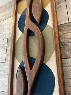 a wooden cutting board sitting on top of a floor next to a tile covered wall