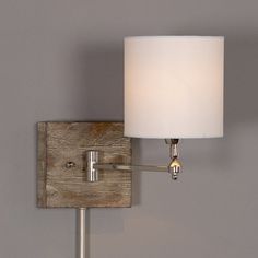 a wall mounted lamp with a white shade on it's side and a wooden frame around the base