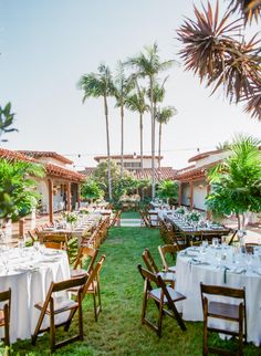 an outdoor dining area with tables and chairs set up for a formal dinner in the grass