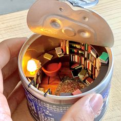 a person is holding a can with books in it and there is a candle inside