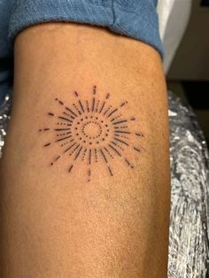 a person with a tattoo on their arm and leg, showing the sun in the middle