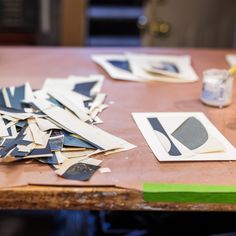 several pieces of cut paper sitting on top of a wooden table next to a paint can