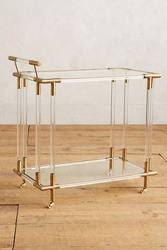 a glass and brass coffee table sitting on top of a wooden floor