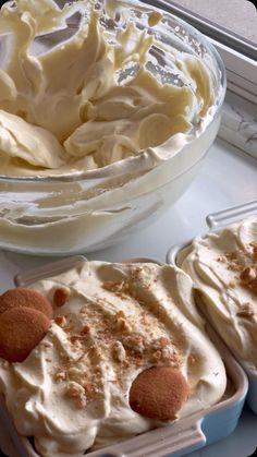 two desserts sitting on top of a counter next to a bowl of whipped cream