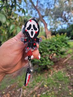 a hand holding a black and white key chain with a red spooked skull on it