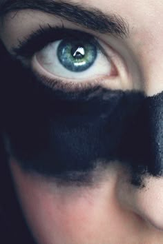 a man's face is covered with black paint and has his eyes painted green