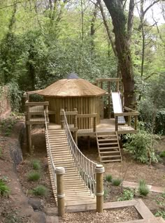 a small wooden structure in the woods with stairs leading up to it's roof