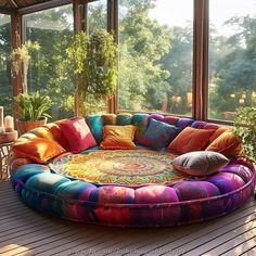 a large circular couch sitting on top of a wooden floor next to a plant filled window