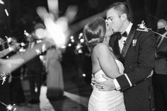 a bride and groom kissing in front of sparklers