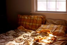 an unmade bed sitting in front of a window