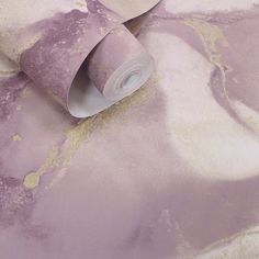 a roll of toilet paper sitting on top of a purple and white wallpaper covered in gold flecks