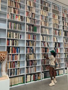 a woman standing in front of a large book shelf filled with lots of books on it