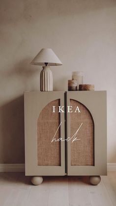 a white cabinet with the words i kea written on it and a lamp next to it