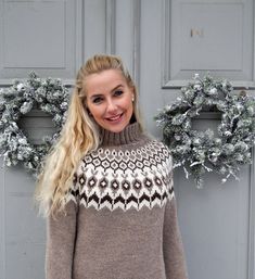 a woman standing in front of a door wearing a sweater