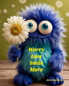 a blue and green stuffed animal holding a white flower with the words worry less smile more on it