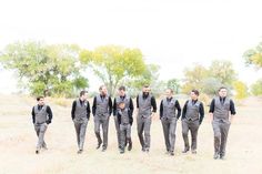 a group of men walking across a grass covered field