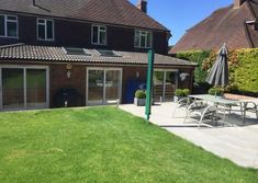 an outside patio with tables and chairs in front of a house on a sunny day