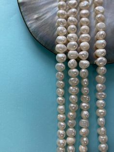 three strands of white pearls hanging from a mirror