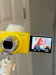 a yellow camera attached to a tripod with a video on the screen next to it