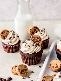 chocolate chip cupcakes with cream frosting and chocolate chips on a plate next to a bottle of milk