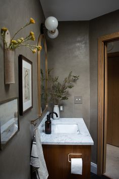 a bathroom sink sitting under a mirror next to a wooden cabinet and wall mounted faucet