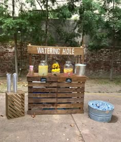 a wooden stand with drinks on it sitting in the middle of a sidewalk next to a brick wall