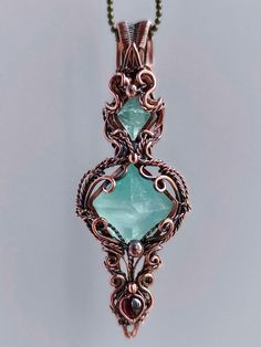 Unveil the magic of nature with this stunning handcrafted wire-wrapped pendant featuring mesmerizing aqua blue fluorite crystals. This unique piece showcases the beauty of raw gemstones embraced by intricate copper wirework, creating a wearable work of art that's sure to captivate. Key features: * Handmade with meticulous attention to detail * Two raw fluorite crystals in a captivating aqua blue hue * Intricate copper wire wrapping in a beautiful, organic design * Antiqued copper finish for a vi Luxury Metal Wire Wrapped Necklaces, Wire Wrapped Key Pendant, Turquoise Apatite Wire Wrapped Jewelry, Handmade Fluorite Pendant Jewelry, Handmade Aquamarine Pendant Jewelry, Aqua Jewelry, Raw Fluorite, Fluorite Crystals, Blue Crystal Necklace