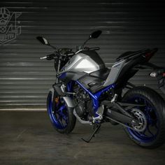 a blue and silver motorcycle parked in front of a garage door