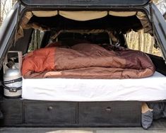 the back end of a truck with an open bed and sleeping bag in the trunk