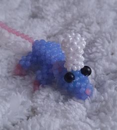 a beaded toy laying on top of a white carpet next to a pink string