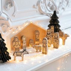 a nativity scene made out of wood and lit up with christmas lights on the mantle