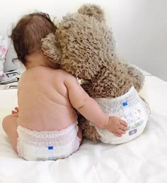 a baby in diapers is hugging a teddy bear