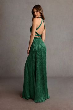 a woman is wearing a green dress and has her back turned to the camera while standing in front of a gray background