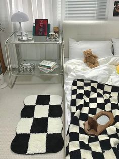 a black and white checkered blanket on a bed next to a table with a teddy bear