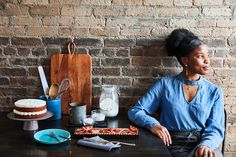 a woman sitting in front of a table with cakes and utensils on it