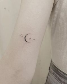 a woman's arm with a small crescent tattoo on the left side of her arm