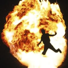 a person jumping in front of a large fireball