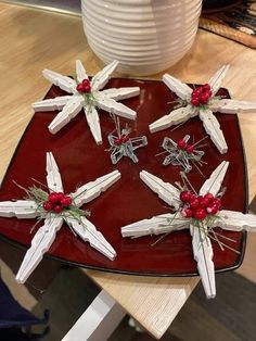 small white crosses are placed on a red plate with holly berries in the center and silver cross pins attached to them