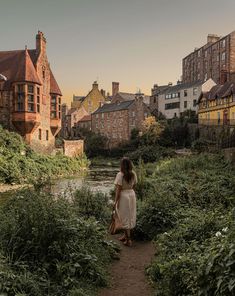 a woman walking down a path next to a river