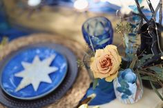 a blue and white table setting with flowers in vases, plates and napkins