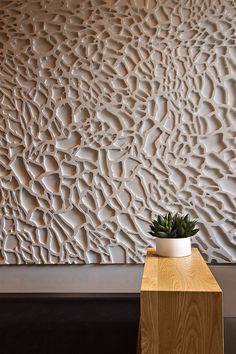 a plant is sitting on a table in front of a wall with an artistic design