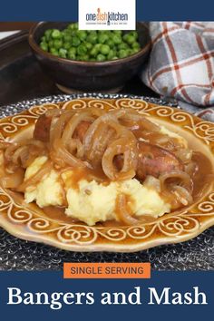 a plate filled with mashed potatoes covered in gravy next to green peas