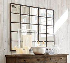 a dresser with some candles on top of it and a large mirror above the dresser