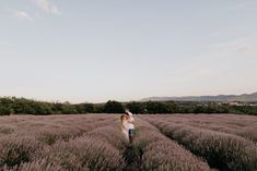 a man and woman walking through a lavender field