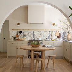 a kitchen with an archway leading into the dining room and kitchen area, along with a table that has two stools on it