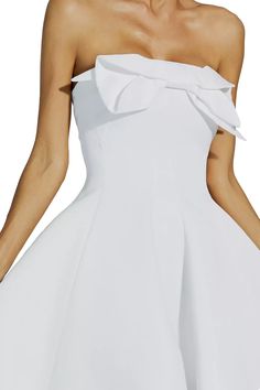 a woman wearing a white dress with a big bow on the top and bottom half